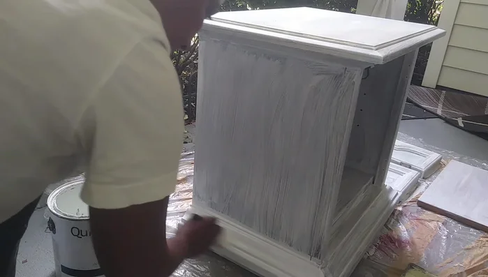 Paint the furniture piece with flat white paint. Use a brush for edges and corners, and a roller for flat surfaces. Apply at least two coats.