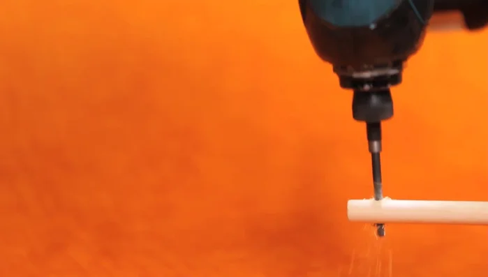 Drill the hole and secure: Use a drill to make a hole in the dowel and put the strap through it, tying off the end.