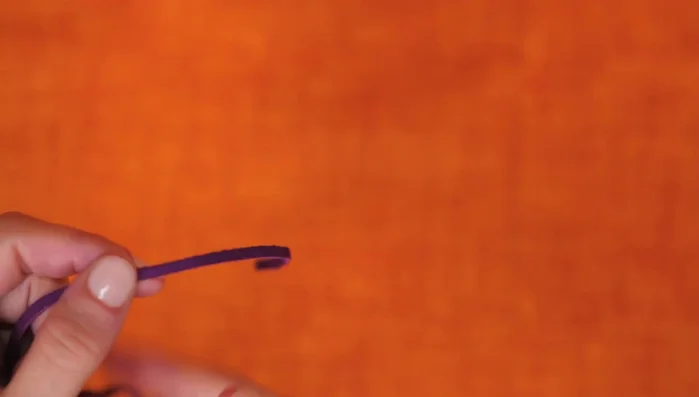 Attach the leather strap: Sew a longer leather strap to the yarn ball.