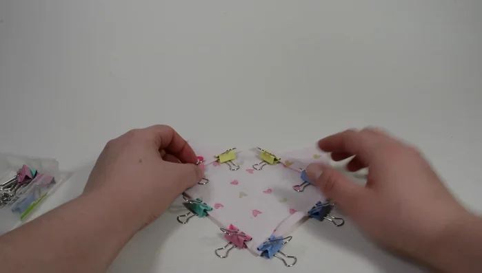 Fold the two corners touching the side without binder clips all the way to the middle, aligning to the edge. Cut both sides at 1/4 inch from the fold and use binder clips to hold.