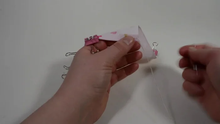 Pass the needle through the double thread of the first hole and pull tightly. Thread all around the folded sides.