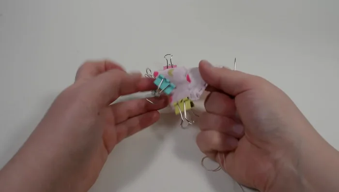 Thread to the other end of the bandana, about 1/8 inch from the middle edge. Flatten out the bandana. Pass the needle through the closest thread circle, create a knot and tighten it. Create another simple knot, cut off the remaining thread leaving about 1/8 inch from the knot.