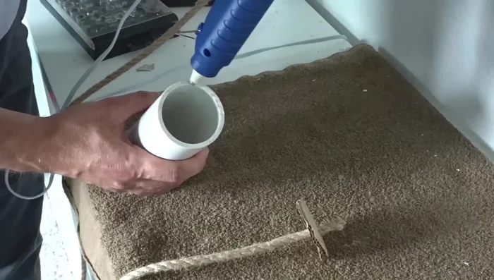 Apply hot glue to the perimeter of the PVC pipe and attach the cardboard.