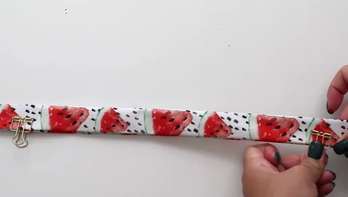 Use binder clips to hold the fabric and strap together. Sew around the entire piece, tucking in the edges at both ends, creating a long rectangle.