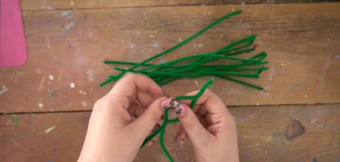 Add more pipe cleaner loops and ribbon weaving to create additional depth and secure the structure. Ensure enough space for flower placement.