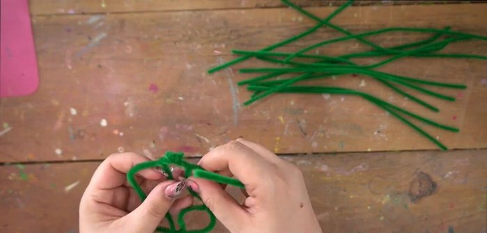 Add more pipe cleaner loops and ribbon weaving to create additional depth and secure the structure. Ensure enough space for flower placement.