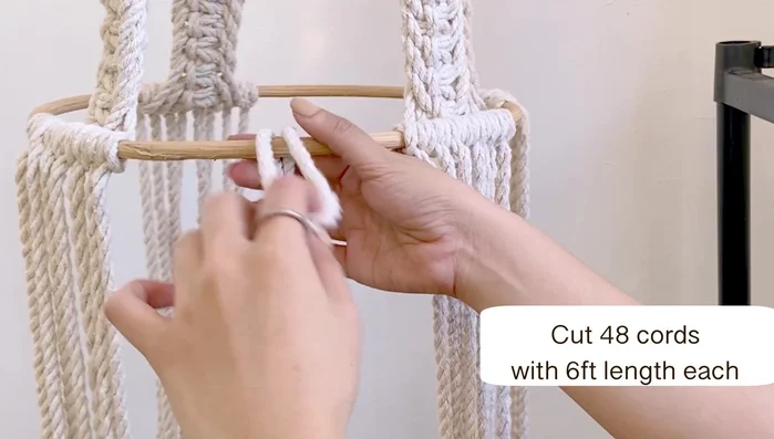 Gather all the bottom cords and tie a simple knot to secure them. Place a square pillow (or similar object) inside the hammock to create shape. Tie a gathering knot at the bottom, using a separate 3-foot cord wrapped around 7 times to create a secure closure. Trim excess cord.