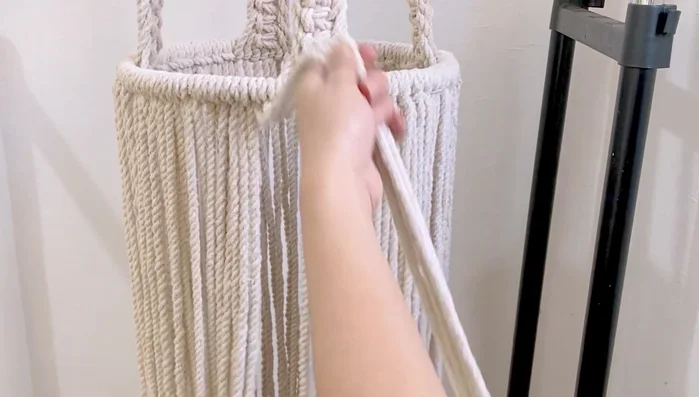 Gather all the bottom cords and tie a simple knot to secure them. Place a square pillow (or similar object) inside the hammock to create shape. Tie a gathering knot at the bottom, using a separate 3-foot cord wrapped around 7 times to create a secure closure. Trim excess cord.
