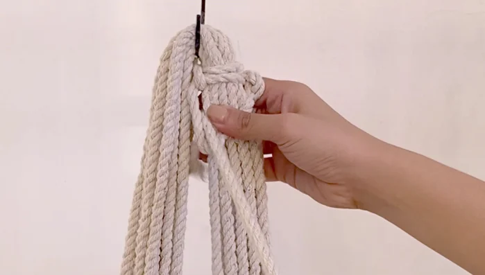 After approximately 8 inches of square knots, find the middle of the cords again and attach them to the S-hook.