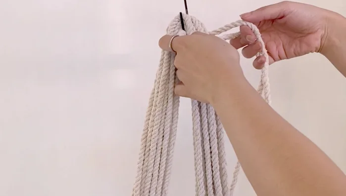 After approximately 8 inches of square knots, find the middle of the cords again and attach them to the S-hook.