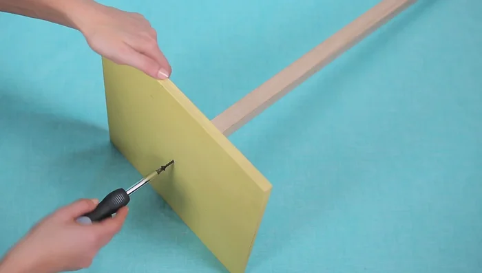 Stack the cardboard squares onto the dowel, starting with the largest and working to the smallest.