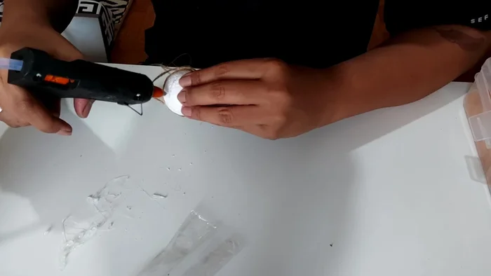Wrap the twine around the styrofoam ball, covering it completely. Press the twine firmly as you go, since the glue isn't hot enough to melt the styrofoam.