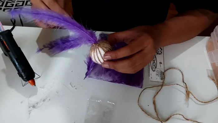 Poke feathers into the glued bottom of the ball, creating a textured surface.