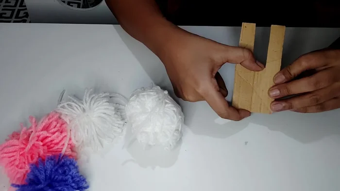 Tie the long threads together tightly to secure the pom-pom.