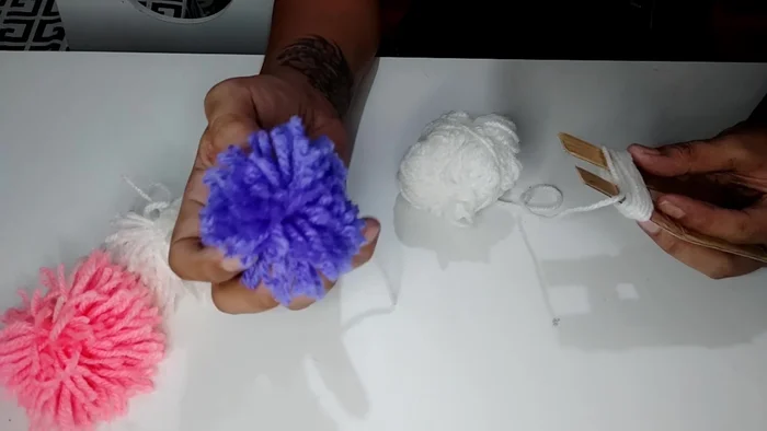 Tie the long threads together tightly to secure the pom-pom.