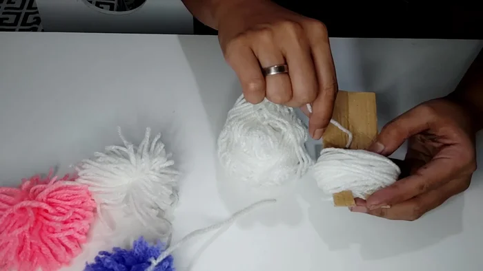 Tie the long threads together tightly to secure the pom-pom.