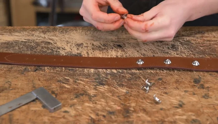 Insert and secure studs: Insert studs, fold the legs over, and tap them flat using a tack hammer.