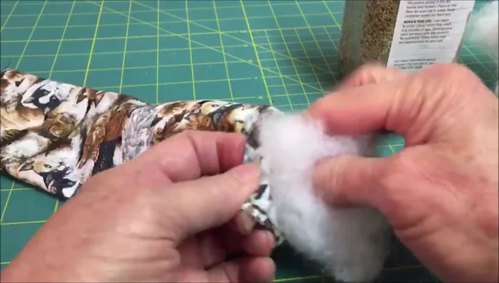 Stuff the fabric tube with about one inch of stuffing, then add catnip (about two tablespoons). Add more stuffing and catnip in sections (the video suggests three). Leave some room at the end for sewing.