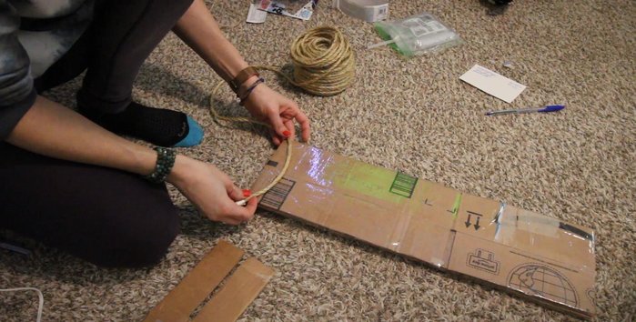 Prepare the sisal rope. Poke a hole in a corner of the cardboard base to secure the rope's starting point. Glue the initial section.