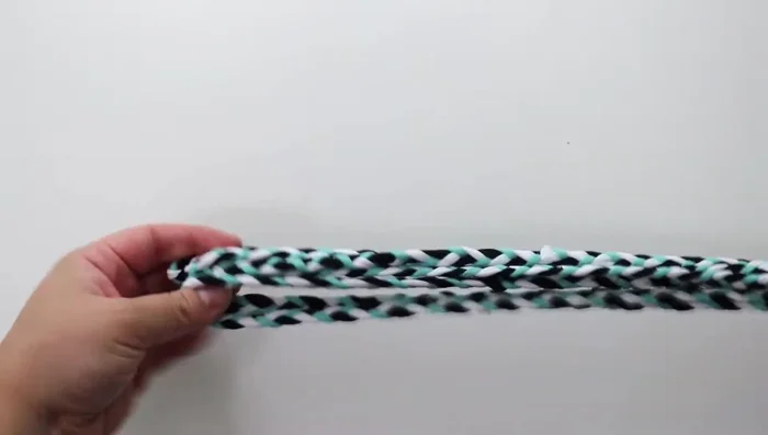 Fold the rope toy in half, and tie a small piece of scrap fabric to one of the strands to mark the midpoint.