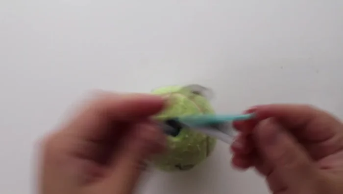 Pull each braided strand through the tennis ball using a safety pin and skewer to guide the pin.