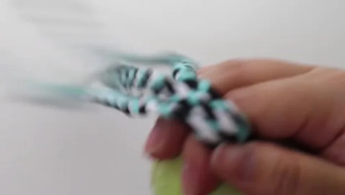 Tie another tight knot after all four braids are through the ball. Continue weaving and complete the rope as with the first toy.