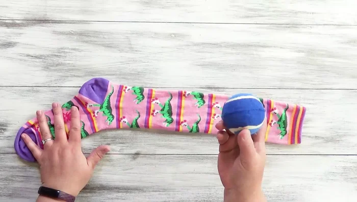 Insert the ball into the sock.