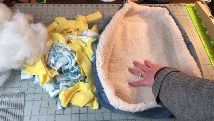 Stuff the bed: Stuff the bed with fleece scraps or polyfill stuffing, starting with the center and then filling the sides. Use both openings to stuff the bed evenly.