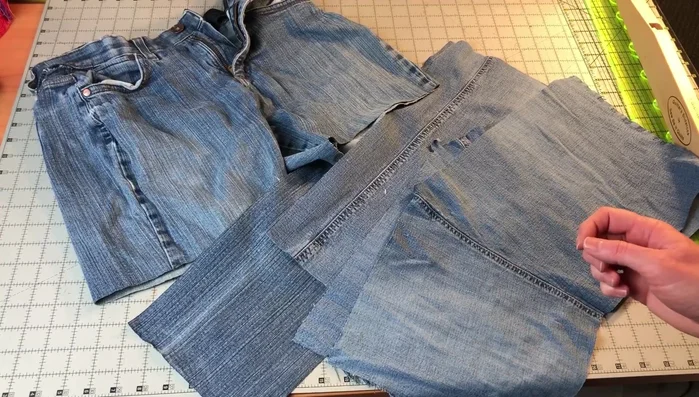 Prepare the jeans: Cut off the legs, turn them inside out, and cut off the seam on one side to flatten. Sew together two jean legs along the long edge to create a rectangular fabric piece.