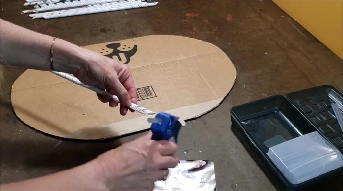 Glue the bottom ends of the rolled magazine paper tubes to the cardboard base, ensuring they stand upright.