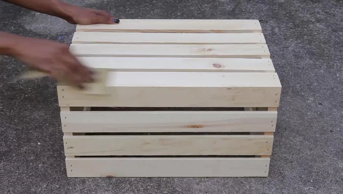 Sand the crate's surface to prep it for painting.