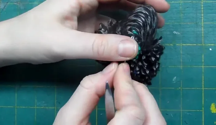 Remove the cardboard. Tighten the initial tie and trim the excess string.