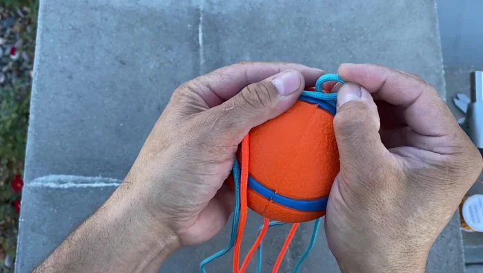 Complete the securing knots: Continue alternating colors and tying underhand knots until you return to the starting point.