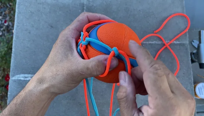 Complete the securing knots: Continue alternating colors and tying underhand knots until you return to the starting point.