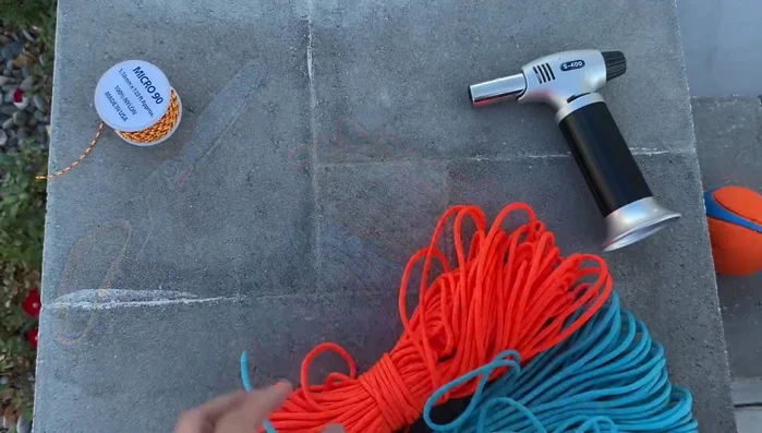 Prepare the cords: Cut three arm's lengths of blue and three arm's lengths of orange paracord. Melt the ends to prevent fraying.