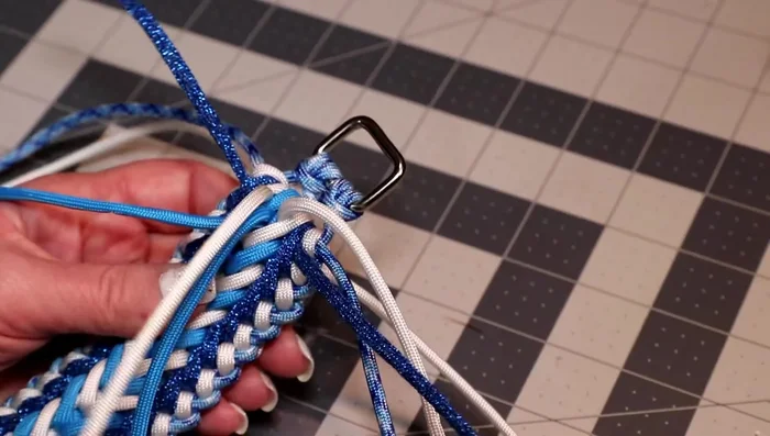 At the end, weave the top white cords through the hole between the cow hitches. Weave the colonial blue cords through their respective holes. Weave the glitter cords through the back stitches.