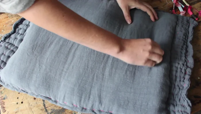 Embroider the circle using three strands of embroidery floss, ensuring the needle goes through all layers and pulling it tight for a quilted look. Add more inner circles as desired.