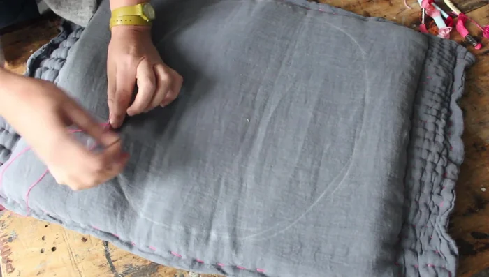 Embroider the circle using three strands of embroidery floss, ensuring the needle goes through all layers and pulling it tight for a quilted look. Add more inner circles as desired.