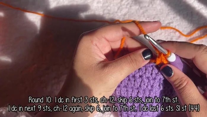 Change to orange yarn. Round 10: (1 double crochet in next 3 stitches, chain 12, skip 6 stitches, join with a single crochet to the 7th stitch, 1 double crochet in the next 9 stitches) repeat. 