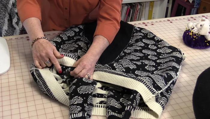 Pull both ends of the sweater together to meet in the middle, creating a gap in the corner. Match up the bottom and sleeve seams.