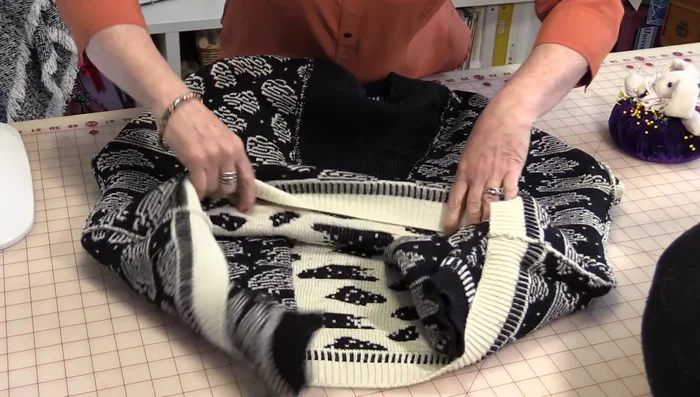 Pull both ends of the sweater together to meet in the middle, creating a gap in the corner. Match up the bottom and sleeve seams.