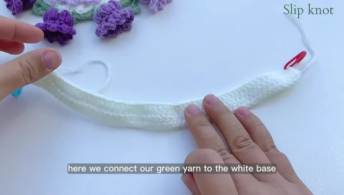 Green base row 2: Single crochet in the first stitch. Chain 7. Find the fourth space from the hook and slip stitch. Chain 3, single crochet through the large space (5 chains from previous row). Continue with the pattern.