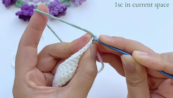 Green base row 2: Single crochet in the first stitch. Chain 7. Find the fourth space from the hook and slip stitch. Chain 3, single crochet through the large space (5 chains from previous row). Continue with the pattern.