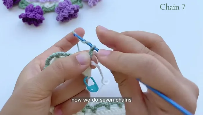 Green base row 2: Single crochet in the first stitch. Chain 7. Find the fourth space from the hook and slip stitch. Chain 3, single crochet through the large space (5 chains from previous row). Continue with the pattern.