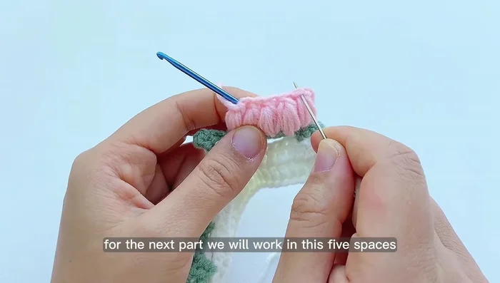 Add flower decorations: Work two double crochets in each of the five stitches on top of the flower clusters. Join with a slip stitch and chain 1.