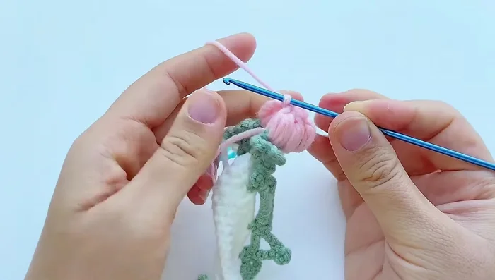 Add flower decorations: Work two double crochets in each of the five stitches on top of the flower clusters. Join with a slip stitch and chain 1.