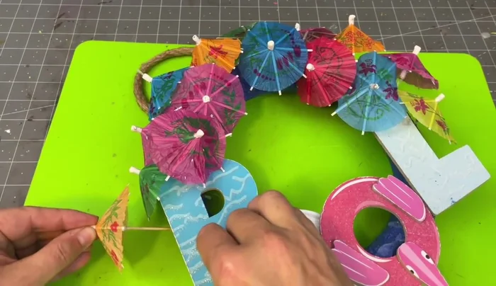 Add the cocktail umbrellas to the sand-covered wreath form.