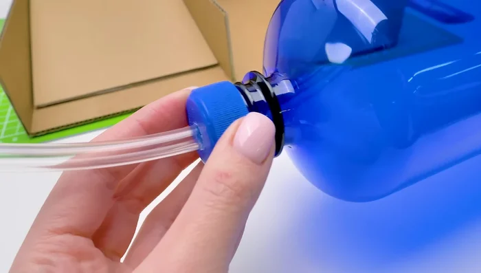 Attach the water fountain to the main cardboard structure. Ensure the water flows properly into the bowl.