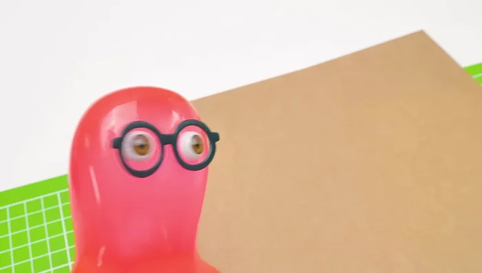 Prepare the cardboard base for the cat food dispenser. Cut out the necessary shapes for the slide and the structure.