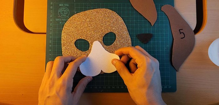 Create holes on both sides of mask and attach strips for wearing.